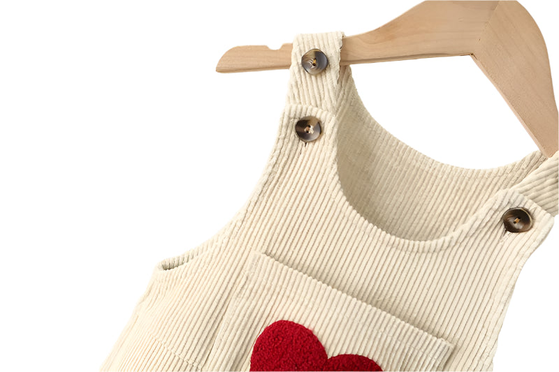 Close up of the adjustable straps on the cream corderoy toddler overalls.