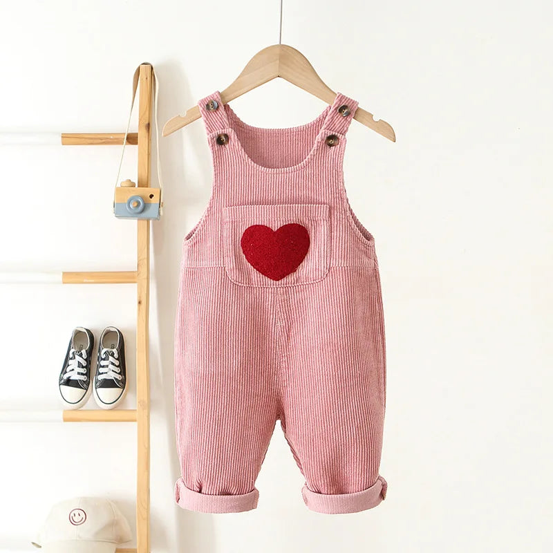 Pink baby and toddler overalls with a front pocket that has a red heart on the front. These baby overall pants have adjustable straps.