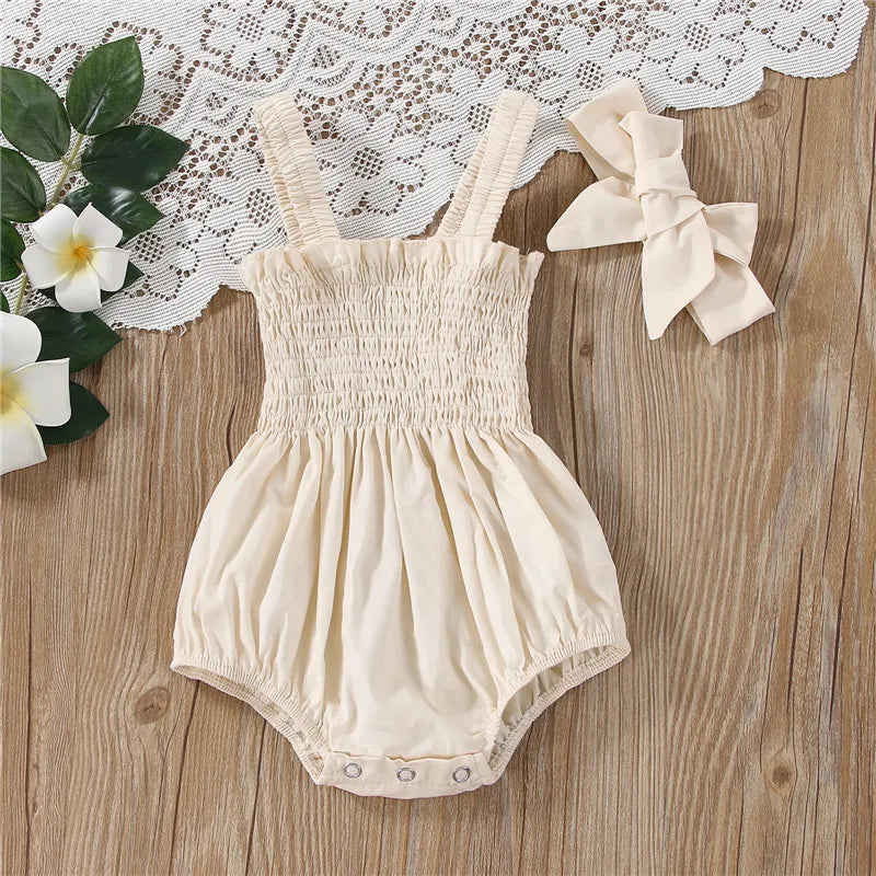 Ivory infant romper with elastic straps at the shoulder a snap bottom and an elastic top with a bow.