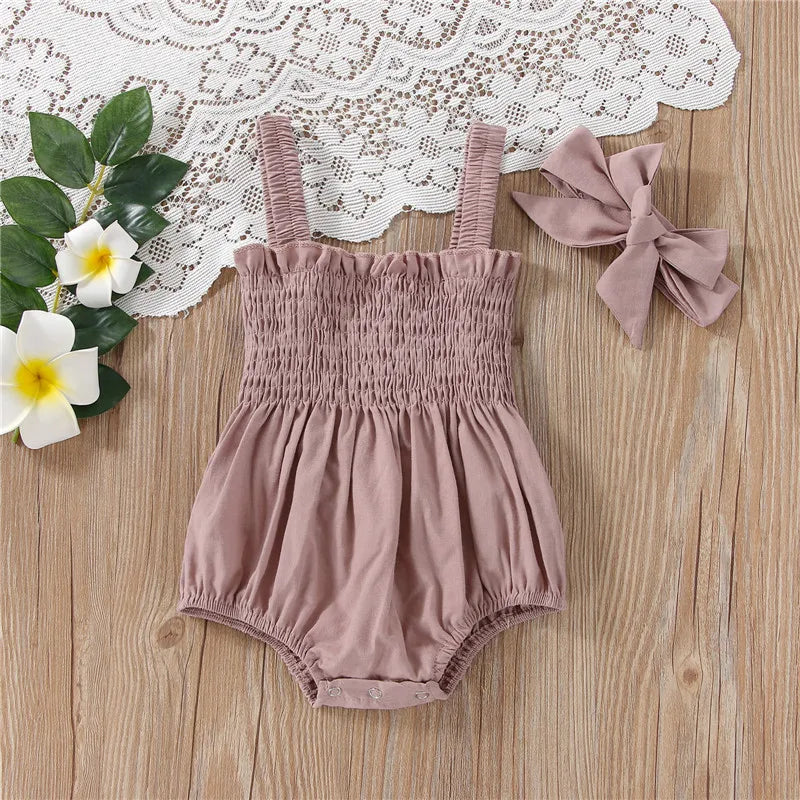 Pink infant romper with elastic straps at the shoulder a snap bottom and an elastic top with a bow.