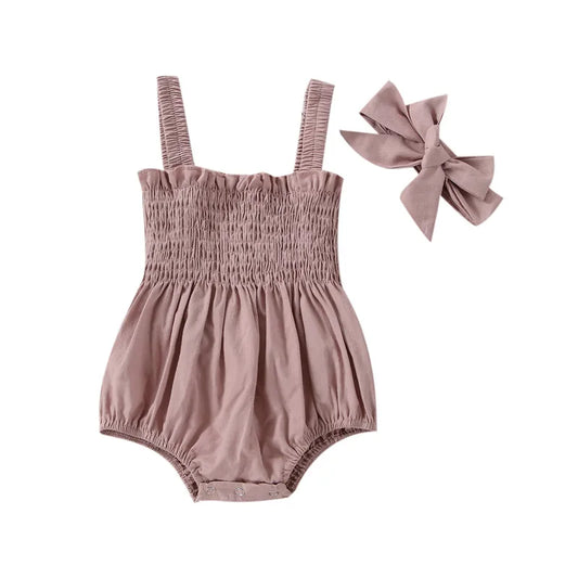 Pink infant romper with elastic straps at the shoulder a snap bottom and an elastic top with a bow.