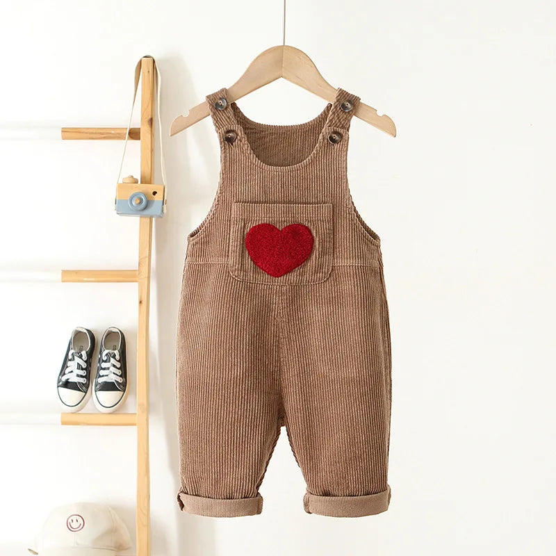 Brown baby and toddler overalls with a front pocket that has a red heart on the front. These baby overall pants have adjustable straps.