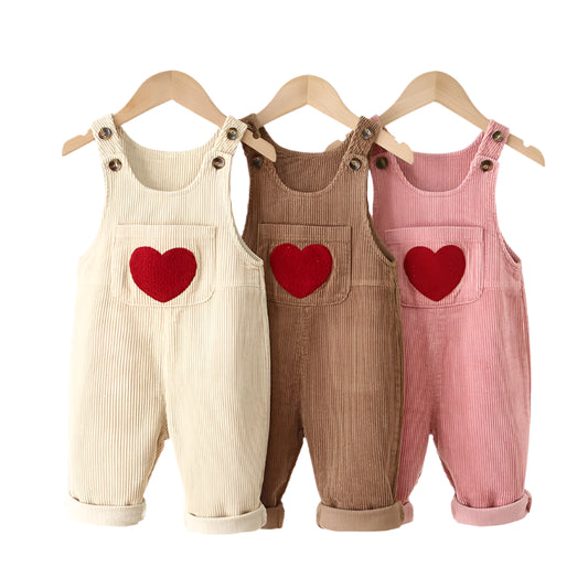 Baby and Kids corderoy overalls in light beige/white, brown and pink. They have a red heart in the front on the front pocket close to the waist. The straps have 2 buttons so they can be adjusted for the childs age.