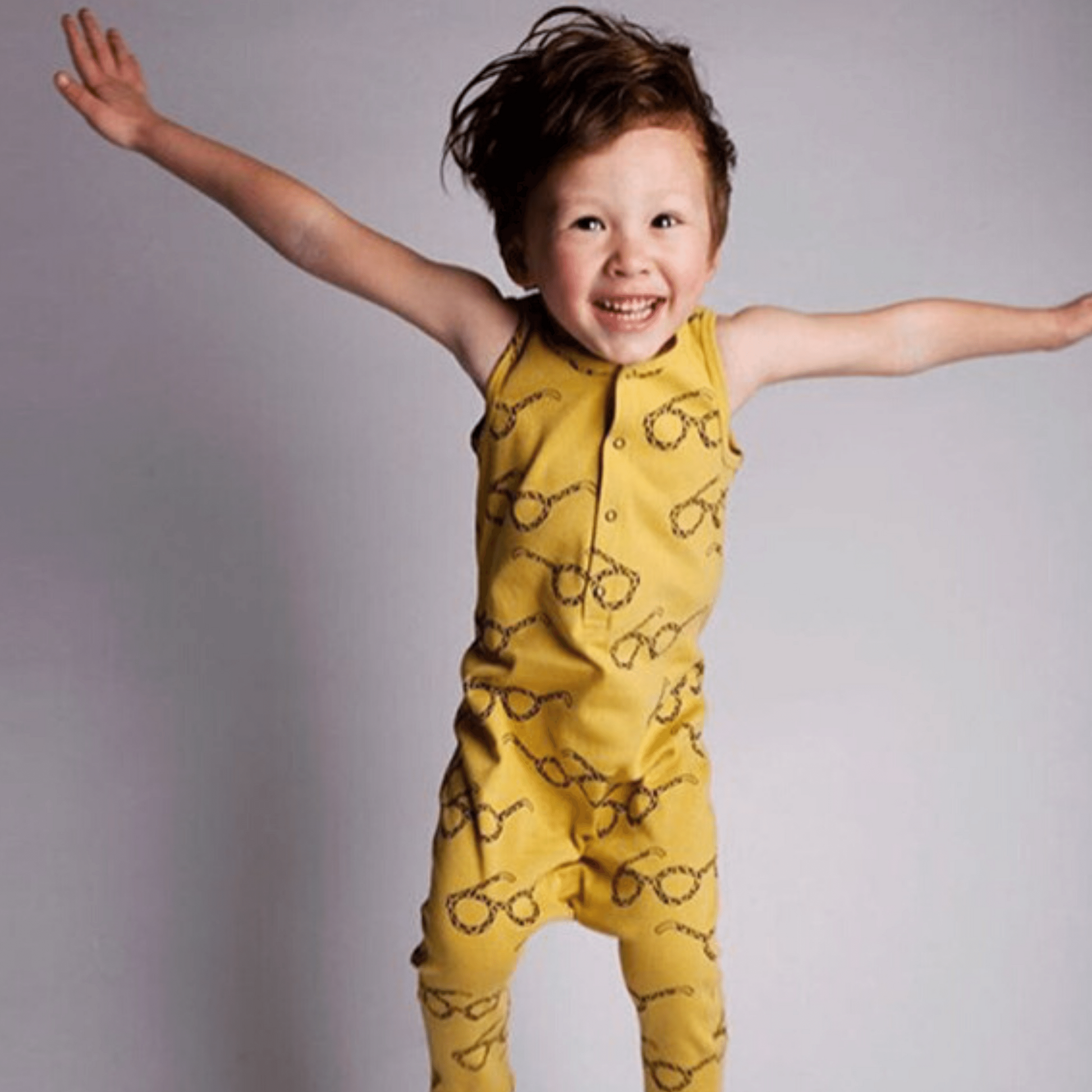 Boy wearing a unisex baby and toddler Rompers  snap bottom  tank with long pants and snap half front in yellow with glasses graphics
