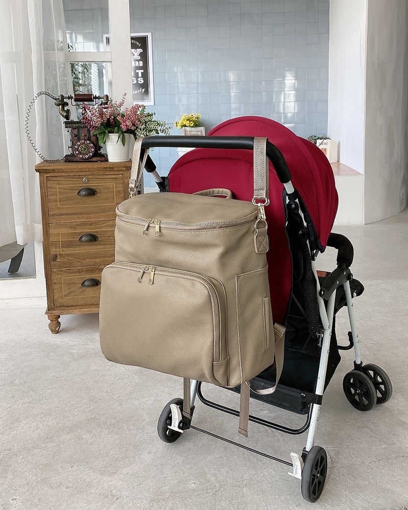 Diaper bag shoulder strap attahces to a stroller