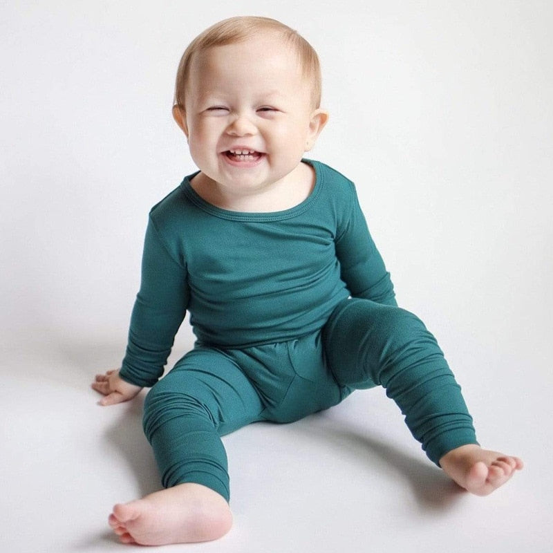 baby sitting on the floor wearing green pajama separates