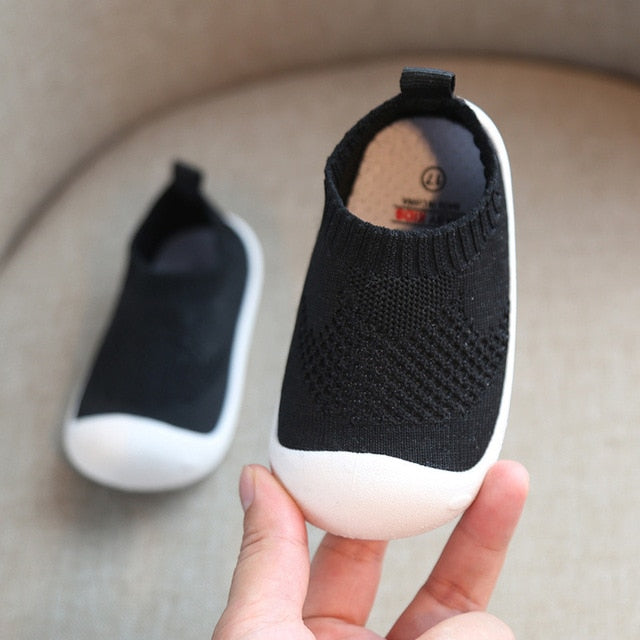 White rubber bottom kids shoes with black uppers that are like ankle socks.