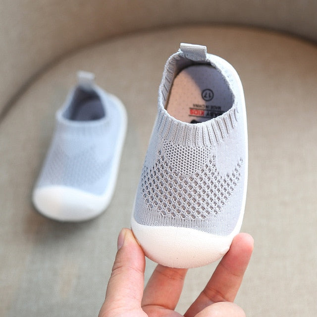 White rubber bottom kids shoes with light grey uppers that are like ankle socks.