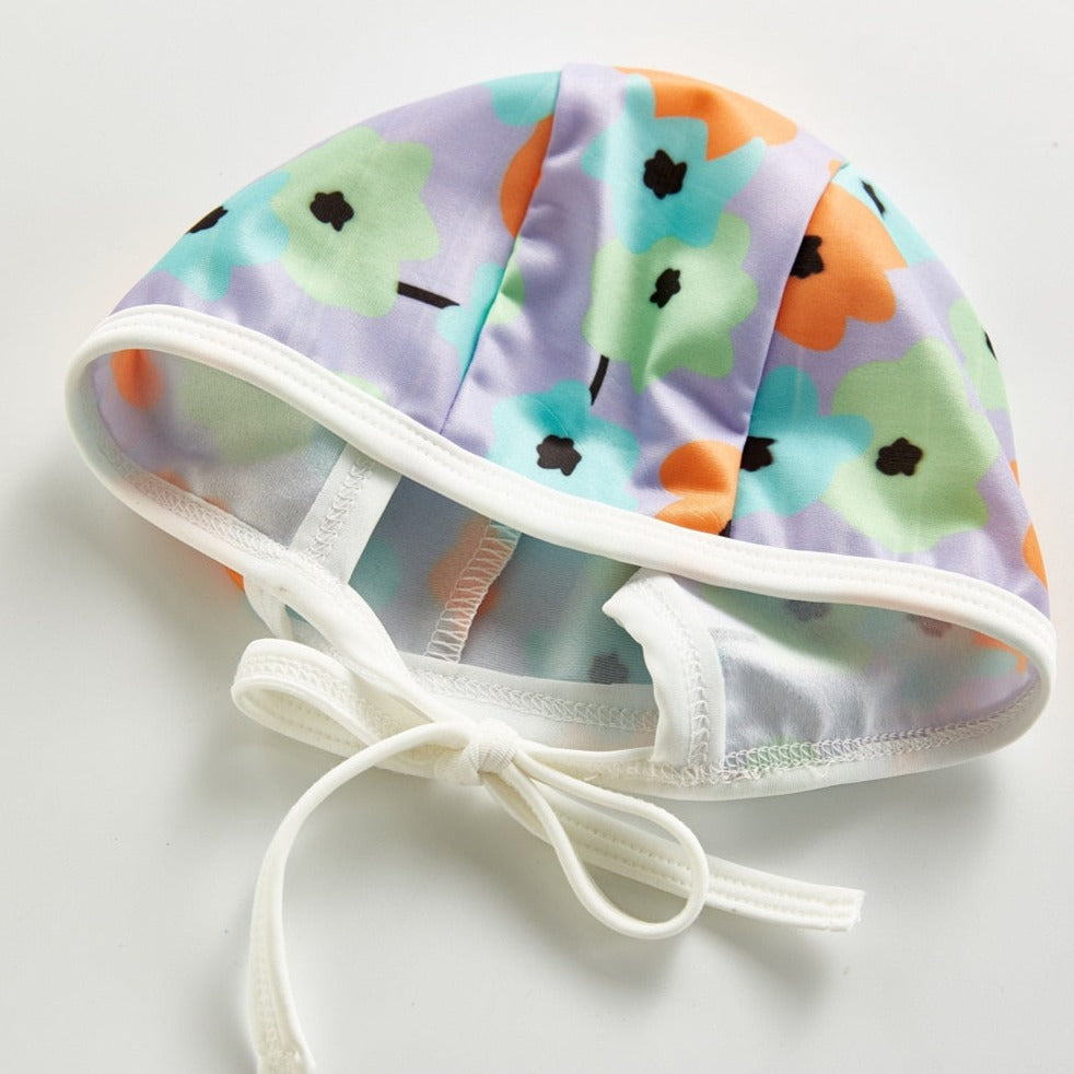 Hat shown fore Infant bathing suit with floer graphics and a hat.