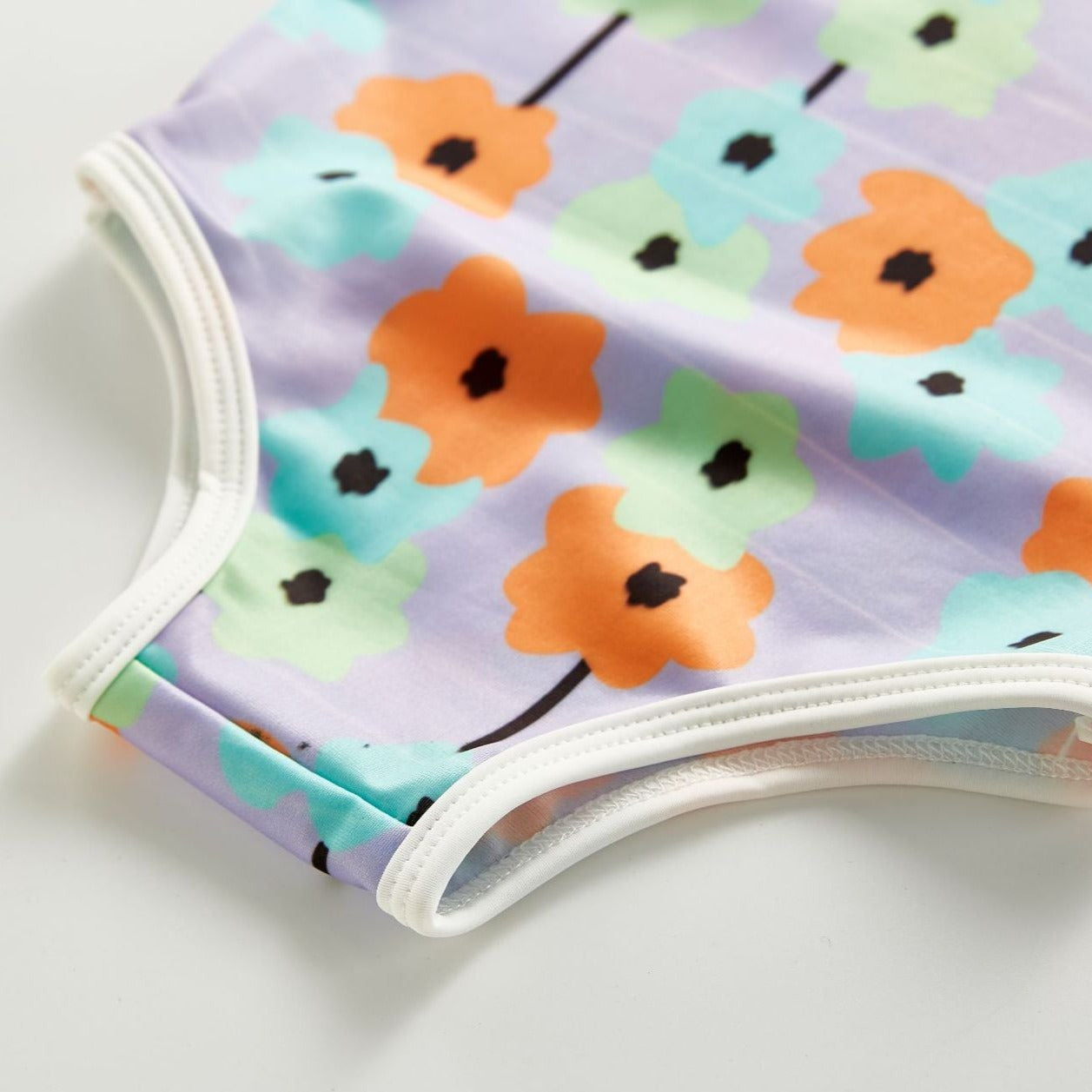 Bottom of bathing suite shown for Infant bathing suit with floer graphics and a hat.