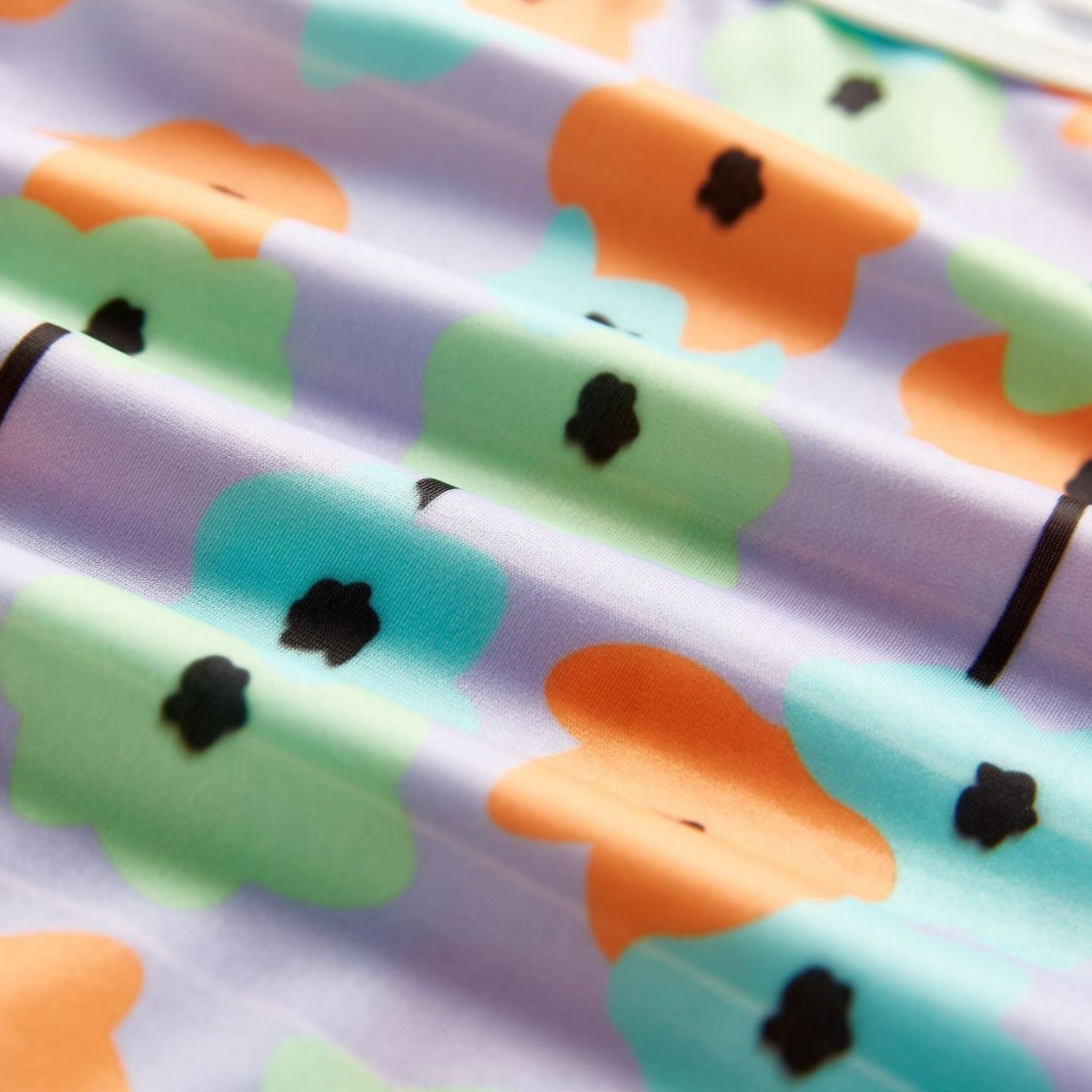Close up of material shown for Infant bathing suit with floer graphics and a hat.