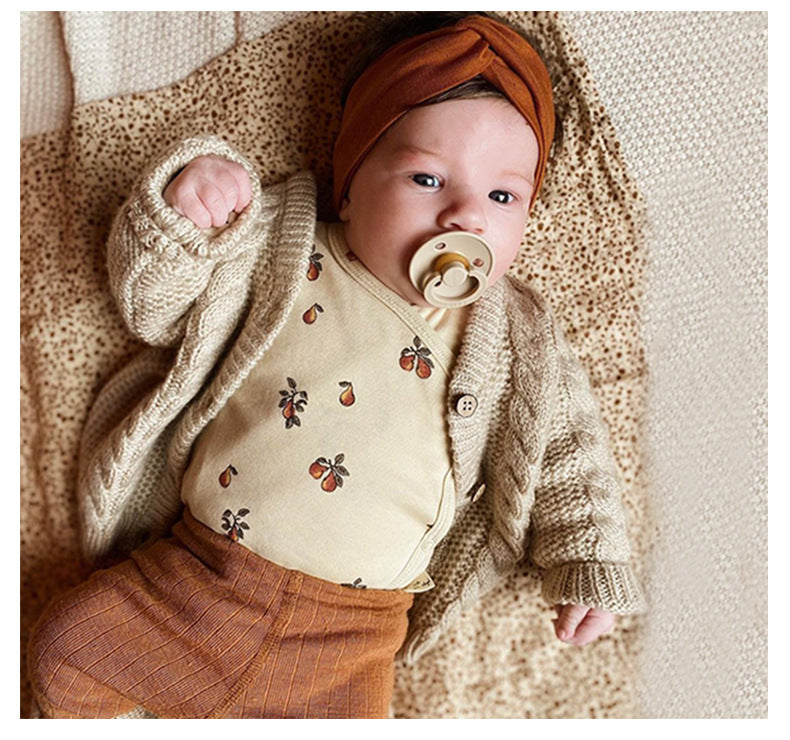 Baby wearing 2 Piece set, long sleeved onesie with side and bottom snaps and leggings with a pacifier in its moth, berry pattern.