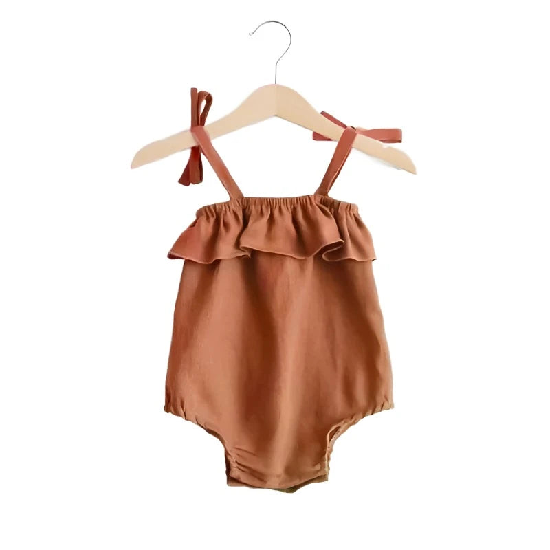 Baby romper in orange burnt umber with ties at the shoulders and a snap bottom. 