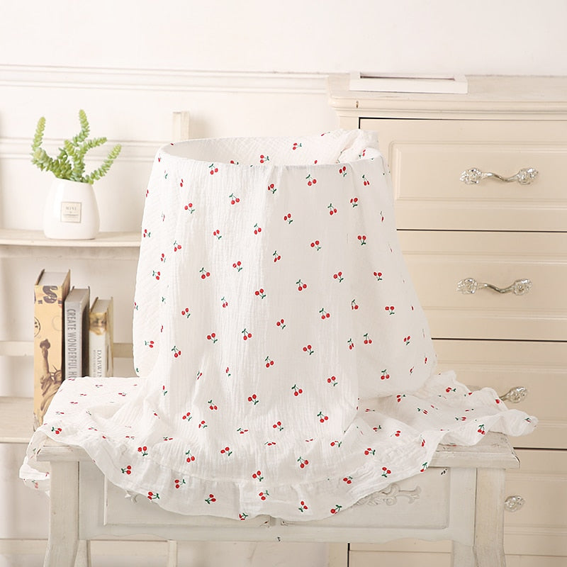 mini cherries on white organic cotton recieving blanket with ruffles in the edge. 