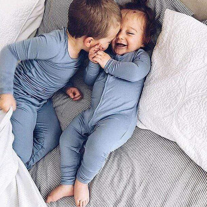 little boy kissing a baby wearing matching bamboo pajamas in blue