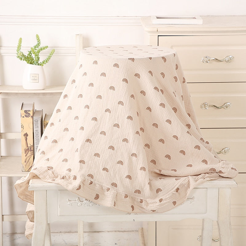 beige organic cotton recieving blanket with ruffles in the edge.  with brown rainbows