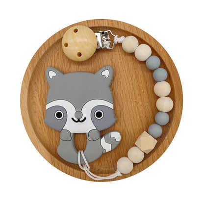 Grey Raccoon Silicone and Wood Pacifier Clip and teether set in wooden circular tray