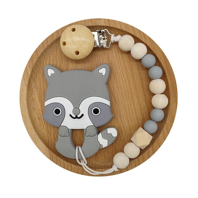 Raccoon Silicone and Wood Pacifier Clip and teether set in wooden circular tray