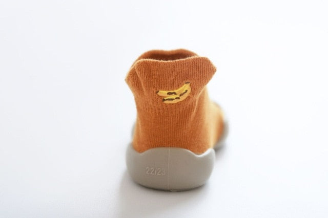 orange baby first walker shoes, with a banana decal. 