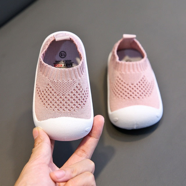 White rubber bottom kids shoes with soft pink uppers that are like ankle socks. 