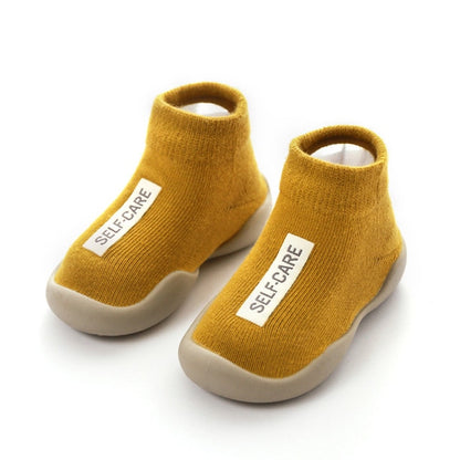 Mustard Yellow first walker sock shoes with a self care lable on the top of the arch. 