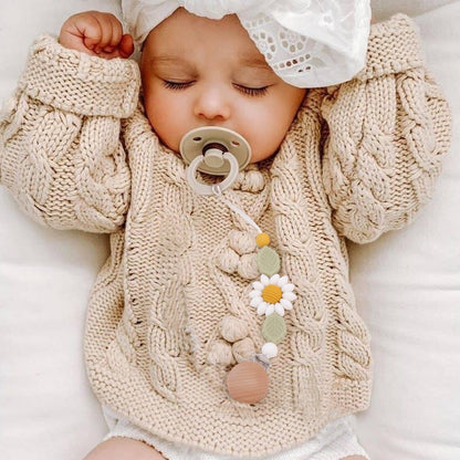 infant with cableknit sweater with the sunflower pacifier clip