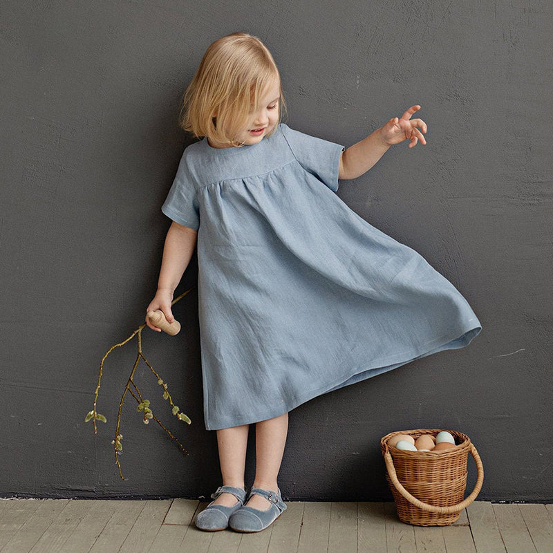 Little girl wearing a classic blue linnen dress with short sleeves. 