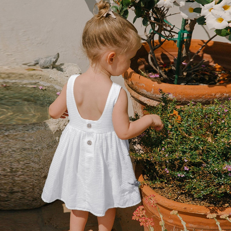 Little girl wearing a white summer knee-length dress